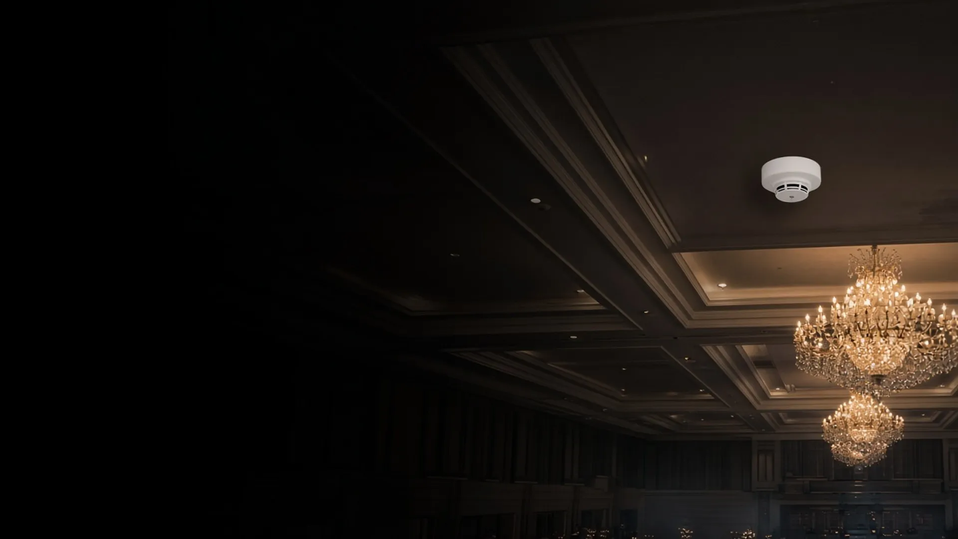 A ceiling-mounted smoke detector in an elegant event hall