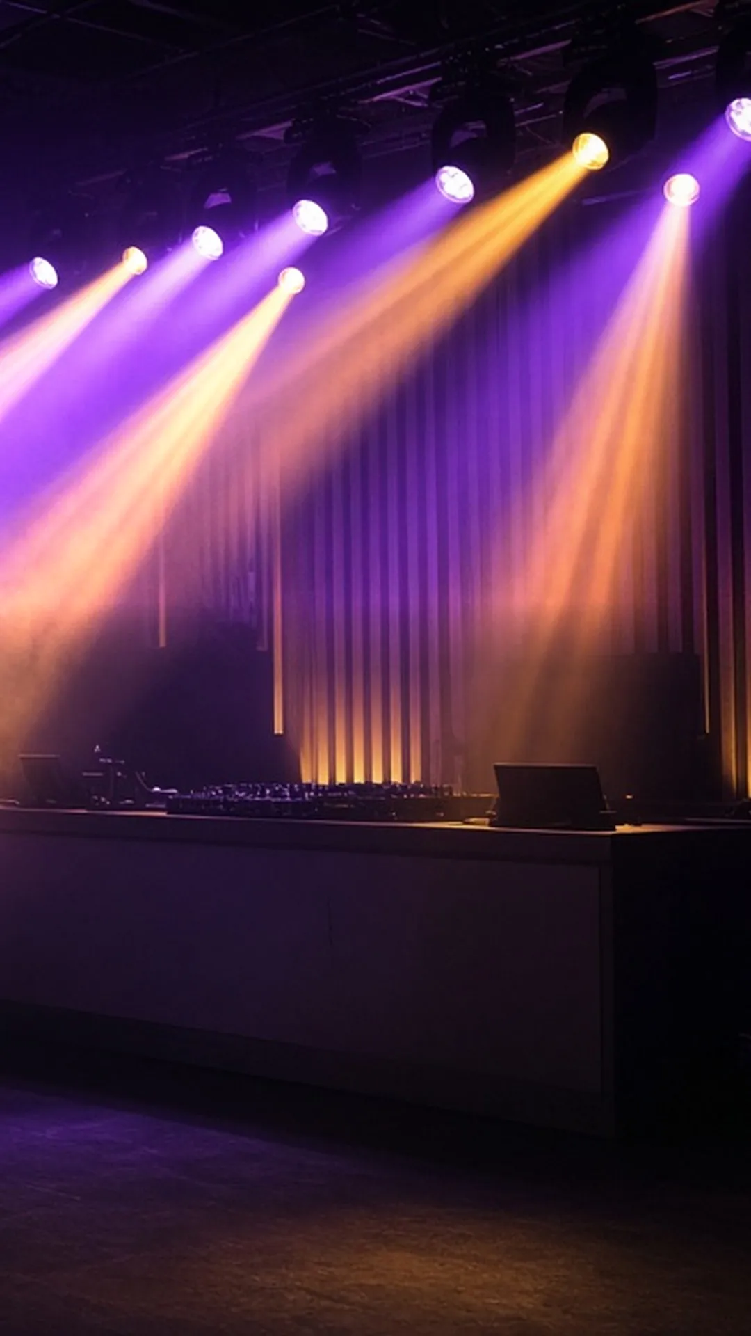 Moving-head light beams fanning through haze above an empty DJ booth