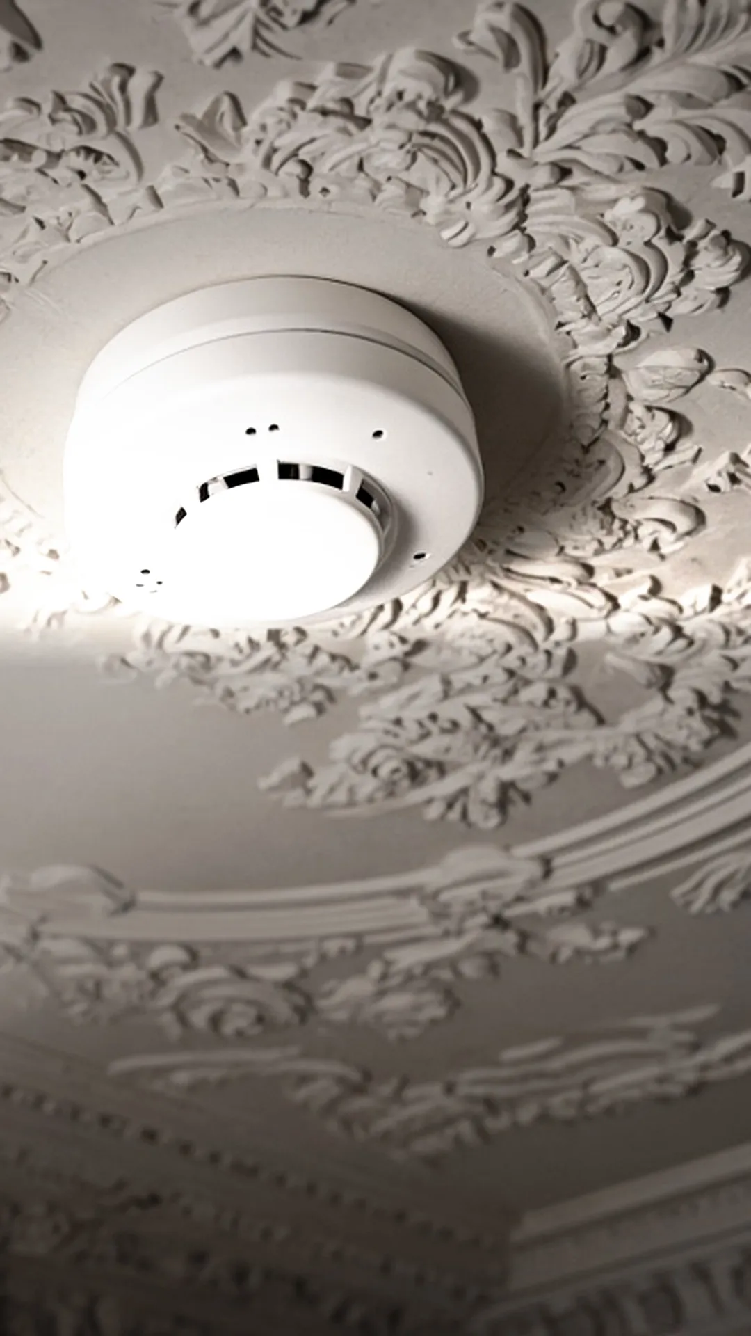 A white ceiling smoke detector in sharp focus